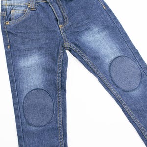 May include: Blue denim jeans with two circular patches on the knees.