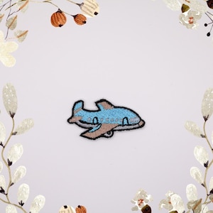 Peut inclure: Un patch brodé d'avion bleu et marron.