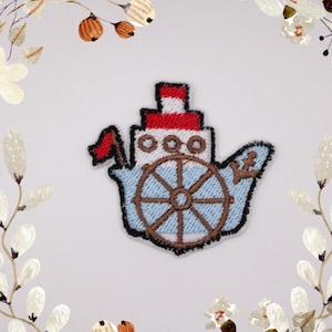 Könnte beinhalten: Ein gestickter Bügel-Patch, der ein Cartoon-Boot in Blau und Weiß mit einem rot-weiß gestreiften Mast und einem braunen Steuerrad zeigt.