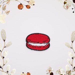 May include: Red embroidered iron-on patch of a macaron with white filling.
