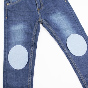 Peut inclure: Un jean bleu denim avec deux empiècements en tissu bleu clair sur les genoux.