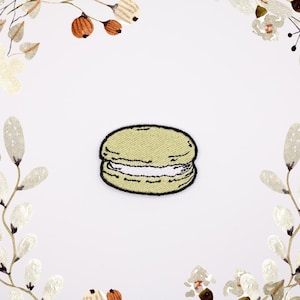 Może przedstawiać: Żółta haftowana naszywka z makaronikiem z białym lukrem, do prasowania.