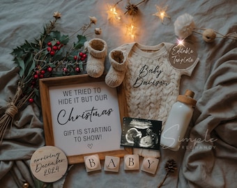 May include: A Christmas-themed pregnancy announcement with a framed sign that reads "We tried to hide it but our Christmas gift is starting to show!"  A wooden circle with the text "arriving December 2024" is next to the sign.  A baby onesie with the text "Baby Davison" is on a gray blanket with a white bottle, a wooden block spelling "BABY", and a small ultrasound image.