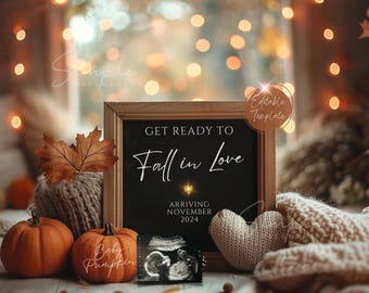 May include: A chalkboard sign with the text "Get Ready to Fall in Love" and "Arriving November 2024". The sign is surrounded by autumnal decorations, including pumpkins, a knitted heart, and a leaf.