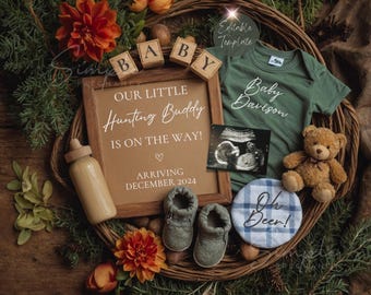 May include: A wooden sign with the text "Our Little Hunting Buddy Is On The Way!" and "Arriving December 2024".  A green onesie with the text "Baby Davison" is next to the sign.  A small wooden bottle, a pair of baby shoes, and a teddy bear are also in the image.