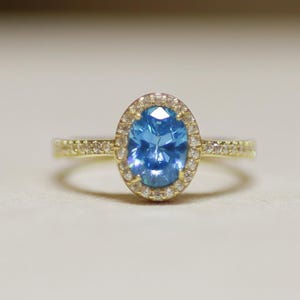 Anillo de oro de 14 quilates con halo de circonita azul: una joya de compromiso delicada
