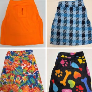 May include: A collection of four sleeveless pet shirts featuring a leash hole on the back. The shirts include a solid orange design, a blue and black plaid pattern, a multi-colored tie-dye print, and a black fabric with colorful bone and paw prints.