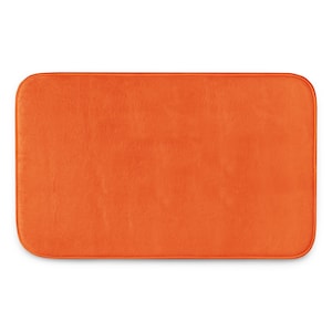 May include: A rectangular bath mat in a solid, vibrant orange colour. The mat features a soft, plush texture across its entire surface and is finished with rounded corners and a matching orange fabric border that frames the rectangular shape.