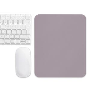 Puede incluir: Un teclado, un ratón y una alfombrilla de ratón rectangular de color lavanda. El teclado es blanco con teclas negras y letras blancas. El ratón es blanco y de forma ovalada. La alfombrilla es de color liso.