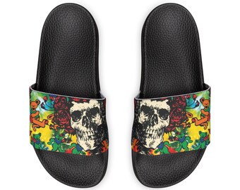 Könnte beinhalten: Paar schwarze Schlappen mit farbenfrohem Design. Die Sandalen haben eine schwarze Schädel- und Rosen-Grafik auf dem Riemen, mit tanzenden Bären und Batikmustern. Die Sohlen sind schwarz und strukturiert.