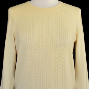 May include: A white ceramic mug with a black handle and the text "But First, Coffee" in a black, bold font. The mug is on a white surface.