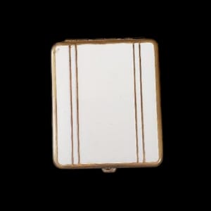 May include: A rectangular, white compact with gold trim and three vertical gold stripes. The compact has a small clasp at the bottom. The background is black.