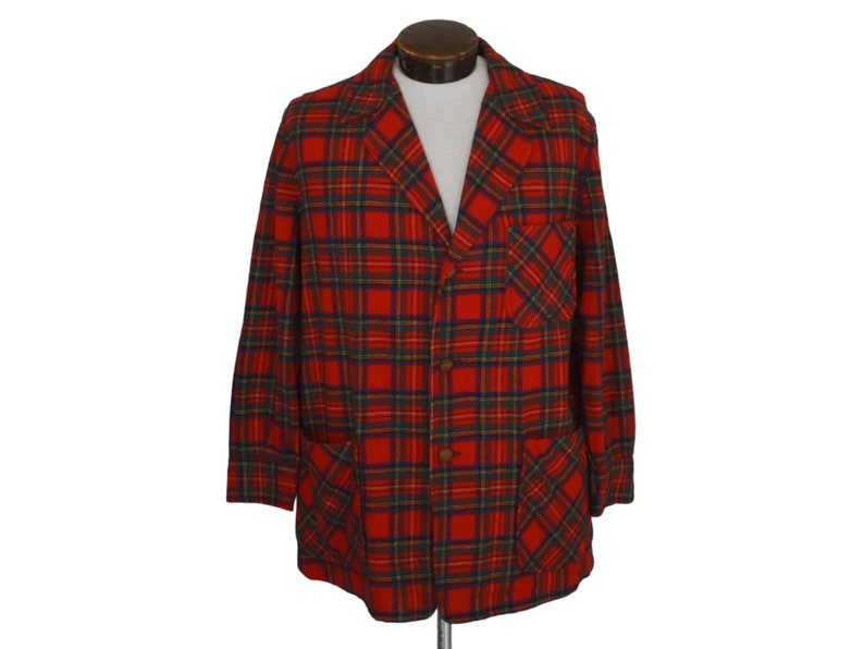 Puede incluir: Un blazer a cuadros rojos con un dise&ntilde;o cl&aacute;sico. La chaqueta presenta un cierre de botones tradicional, dos bolsillos delanteros y un bolsillo en el pecho. El patr&oacute;n de cuadros incluye l&iacute;neas rojas, verdes y azul marino. El blazer se muestra en un maniqu&iacute;.