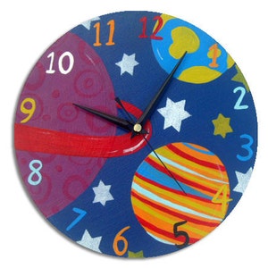 Può includere: Un orologio rotondo blu con pianeti e stelle colorati. I numeri da 1 a 12 sono visualizzati attorno al quadrante dell'orologio. Le lancette dell'orologio sono nere.