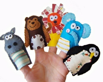 Könnte beinhalten: Fünf Fingerpuppen aus Filz, jede zeigt ein anderes Tier: ein graues Flusspferd, ein brauner Affe, ein roter Löwe, ein blauer Elefant und ein schwarzer Pinguin. Die Puppen tragen alle Kleidung und haben gestickte Details.