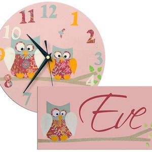 K&ouml;nnte beinhalten: Rosa Uhr mit Eulen-Motiv, wei&szlig;em Hintergrund und schwarzen Zeigern. Die Uhr hat die Zahlen 1 bis 12 und zwei Eulen mit Blumenmustern. Die Uhr wird mit einem rosa Schild mit dem Namen "Eve" in Kursivschrift geliefert.