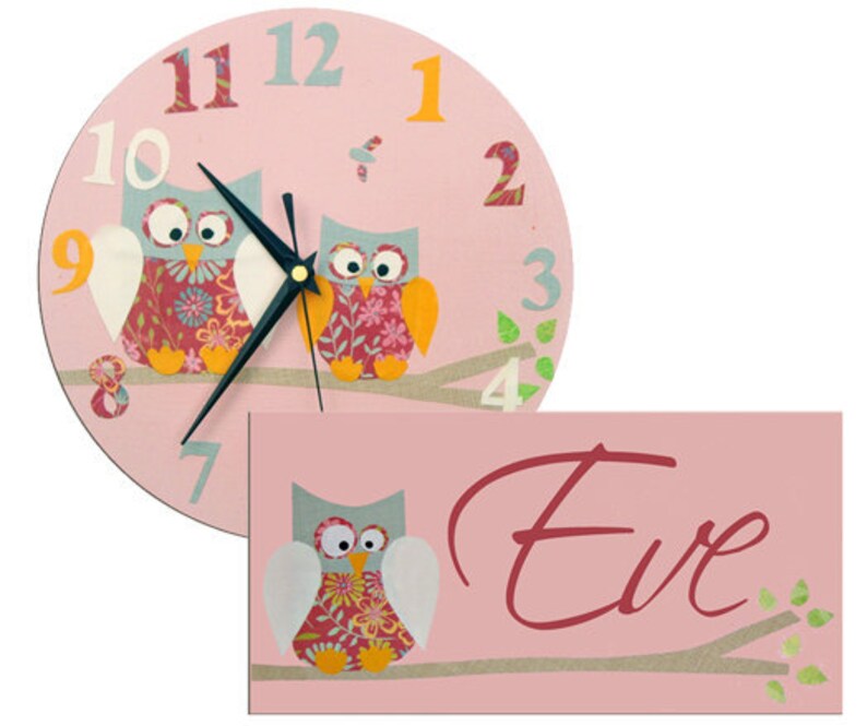 K&ouml;nnte beinhalten: Rosa Uhr mit Eulen-Motiv, wei&szlig;em Hintergrund und schwarzen Zeigern. Die Uhr hat die Zahlen 1 bis 12 und zwei Eulen mit Blumenmustern. Die Uhr wird mit einem rosa Schild mit dem Namen "Eve" in Kursivschrift geliefert.