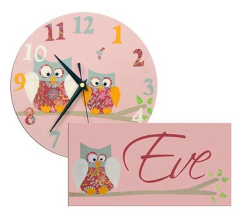 Puede incluir: Reloj rosa con b&uacute;hos y dise&ntilde;o floral, y una placa de nombre a juego con el nombre "Eve" en cursiva.