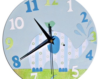 May include: A blue and green children's clock with an elephant design. The clock has a black hour and minute hand and white numbers.