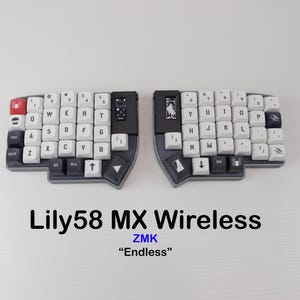 May include: A split ergonomic keyboard, the Lily58 MX Wireless, with white keycaps and a dark gray frame. The keyboard has a compact layout with a red escape key and small screens. The text "Lily58 MX Wireless" and "Endless" are visible.