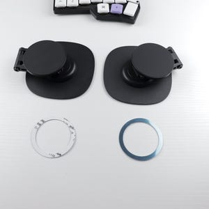 May include: Two black circular metal mounts with a small black lever on the side. Two circular metal rings, one silver and one white, are also pictured.