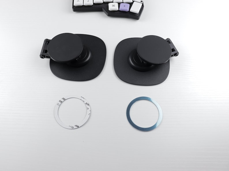 May include: Two black circular metal mounts with a small black lever on the side. Two circular metal rings, one silver and one white, are also pictured.