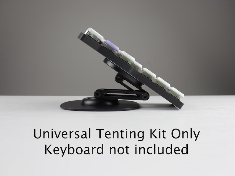 May include: A black universal tenting kit for a keyboard, angled upwards. The kit includes a circular base and an adjustable arm to support the keyboard. The keyboard is not included. Text on the image reads: Universal Tenting Kit Only Keyboard not included.