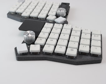 May include: A split ergonomic keyboard with white keycaps and a dark gray base. The keyboard features a rotary encoder and a black connecting bridge. The keys are labeled with letters, numbers, and symbols. The keyboard is designed for comfort and efficiency.