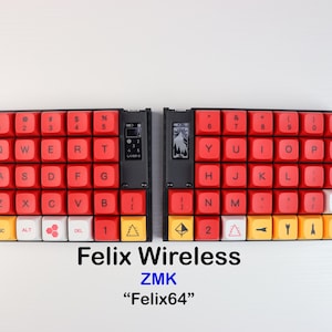 Könnte beinhalten: Eine geteilte ergonomische mechanische Tastatur mit roten Tastenkappen, weißen Akzenttasten und einer gelben untersten Tastenreihe. Das Gerät verfügt über kleine integrierte Bildschirme, ein schwarzes Gehäuse und den Text Felix Wireless ZMK Felix64.