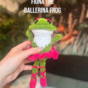 May include: Crochet pattern PDF for Fiona the Ballerina Frog. The frog is green with white yarn for the belly and pink yarn for the tutu and shoes.  Fiona is holding her arms out in a ballerina pose.