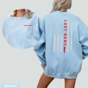 a woman wearing a light blue sweatshirt with an american flag on it