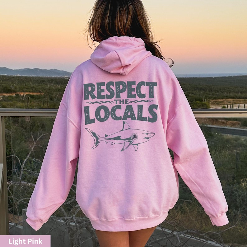 a woman wearing a pink hoodie that says respect the locals