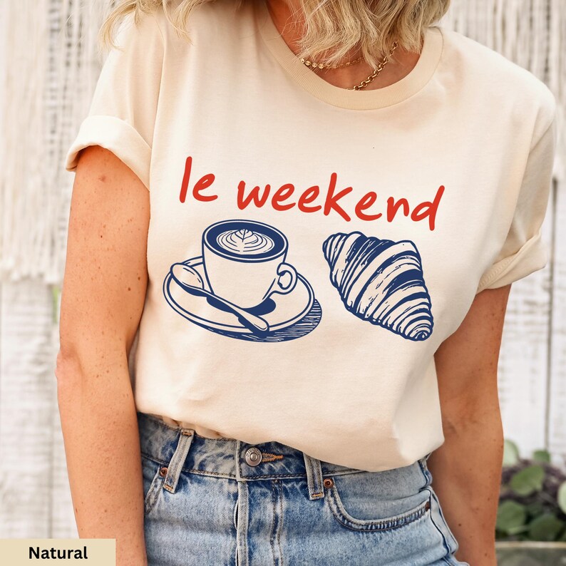 a woman wearing a t - shirt that says le weekend with a cup of coffee