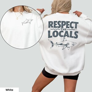 a woman wearing a white sweatshirt that says respect the locals