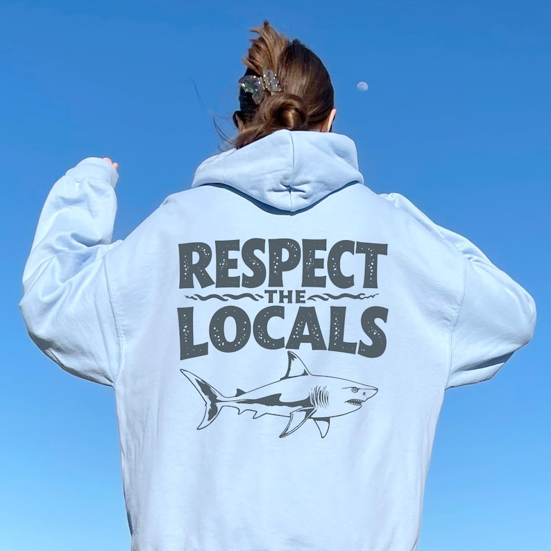 a woman wearing a white hoodie that says respect the locals