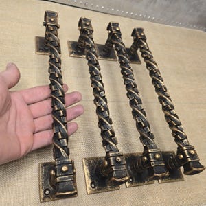 May include: Four antique-style door handles with a twisted design. The handles are made of metal and have a dark brown finish.
