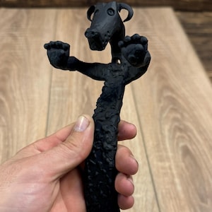 May include: Black metal door handle shaped like a stylized dog with a textured surface.