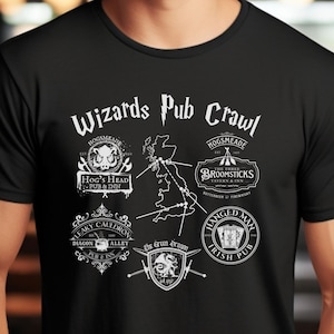 May include: Black t-shirt with a white graphic of a map of the United Kingdom with various pub names and logos, including "Hog's Head Pub & Inn", "Leaky Cauldron", "The Three Broomsticks", and "The Hanged Man Irish Pub". The text "Wizards Pub Crawl" is at the top of the graphic.