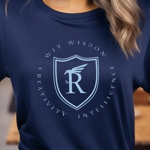 May include: A navy blue t-shirt with a light blue circle design featuring a shield with the letter "R" and the words "Wit, Wisdom, Creativity, Intelligence".
