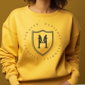 May include: A yellow sweatshirt with a black circle graphic featuring a badger mascot and the words "Loyalty, Justice, Patience, Fairness".