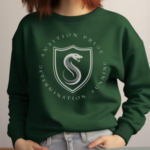May include: Forest green sweatshirt with a white circle graphic featuring a snake and the words "ambition, pride, determination, cunning".