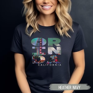 Heather Navy shirt featuring Orinda California text with the iconic Orinda Theatre design integrated into the letters. Simple and stylish, this tee is perfect for showcasing local pride and celebrating Orinda and Lamorinda’s charm