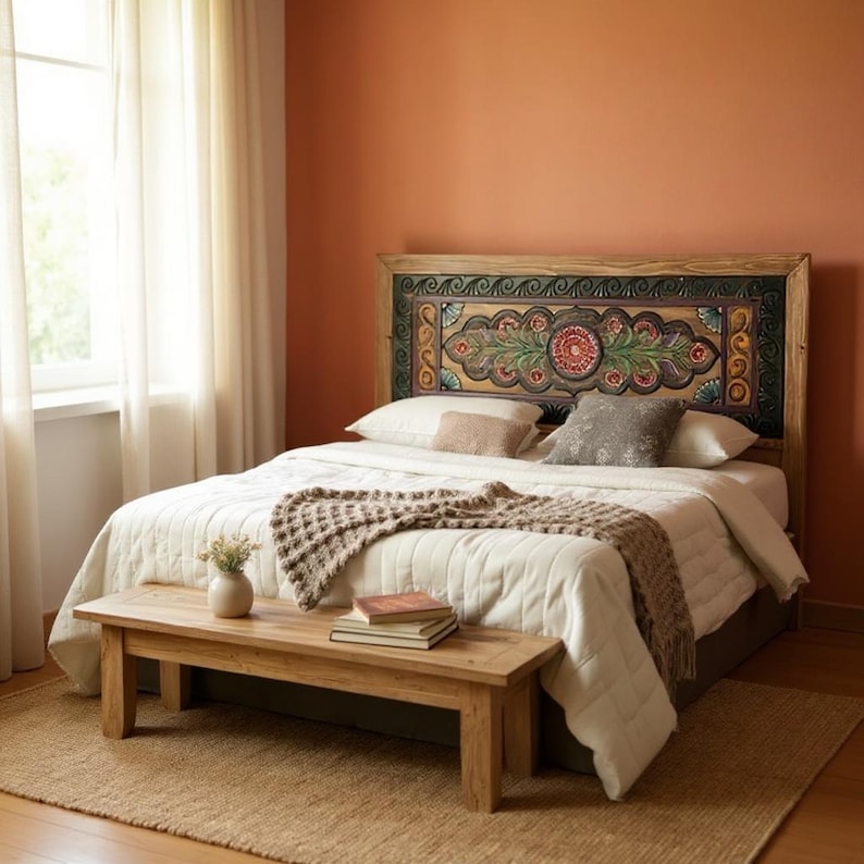 May include: A bedroom with a wooden bed frame and a headboard featuring a colorful floral design. The bed is covered with a white comforter and a brown throw blanket. A wooden bench sits at the foot of the bed.