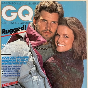 May include: GQ magazine cover featuring a couple wearing winter clothing. The cover text reads "Rugged!" and "Your cold-weather wardrobe to fight winter with style".
