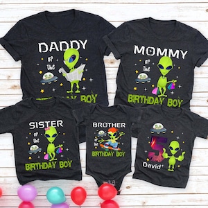 May include: Family matching dark gray t-shirts and a onesie with alien graphics. The shirts read "Daddy", "Mommy", "Sister", and "Brother" with "of the Birthday Boy". One shirt has the number "5" and the name "David".