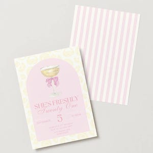 May include: A pink and yellow invitation card with the text "She's Freshly Twenty One" and a watercolor illustration of a champagne glass with a pink bow. The back of the card has pink and white stripes.