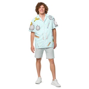 May include: A short-sleeved button-down shirt with a light blue grid pattern and various time-related illustrations, including stopwatches and rulers. The shirt is paired with light gray shorts and white sneakers.
