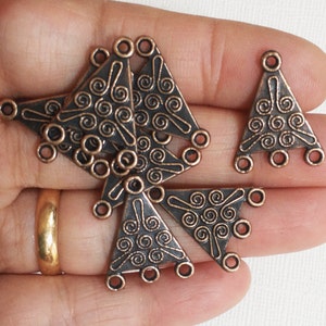 Può includere: Un gruppo di otto connettori triangolari in rame antico con un design a spirale. Ogni connettore ha tre fori per attaccare gioielli o altri oggetti artigianali.