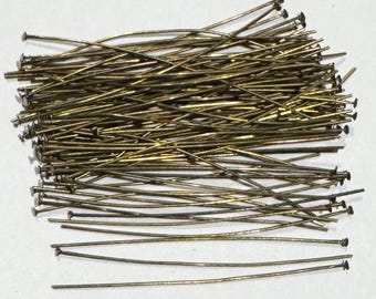 May include: A large pile of gold-colored head pins with flat heads. The pins are arranged in a random pattern and are all the same size.