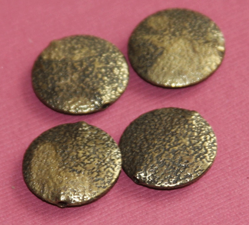 May include: Four round, gold-colored, textured beads with a hole in the center.